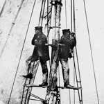 Two men aloft in the rigging of a 19th century sailing vessel.