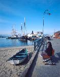 A woman sitting on a bench at Hyde Street Pier.