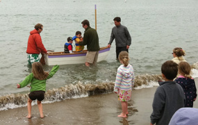 A small boat floating in the water with two children in it. A small boat floating in the water with two children in it.