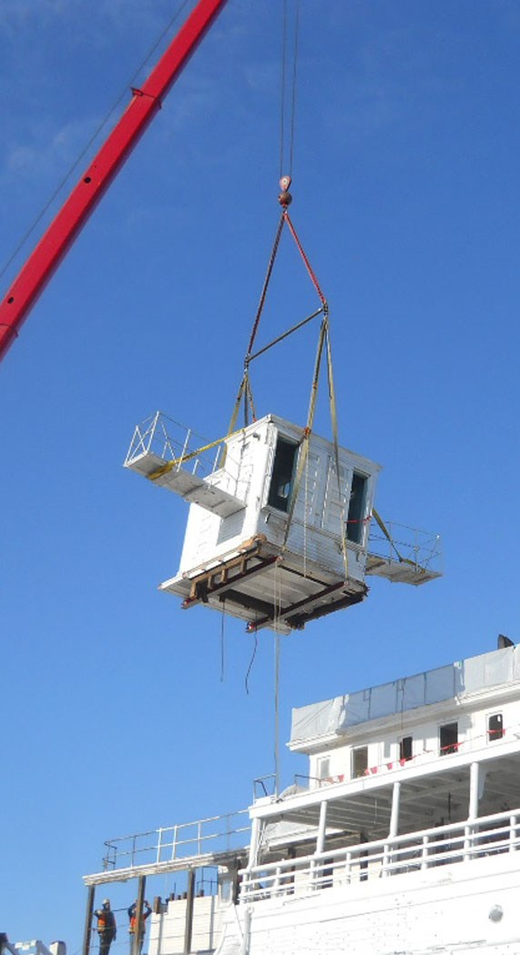 The pilothouse hanging from a crane.
