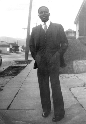 Thomas Fleming standing on sidewalk, wearing a three piece suit and smiling.