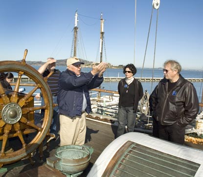 A volunteer near the stern of Balclutha talking with visitors.