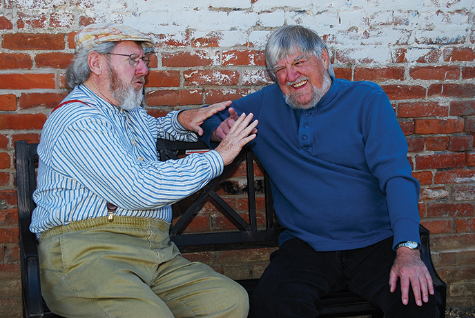 Two older men sitting together and laughing.