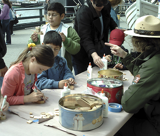 A park ranger with children at a table making crafts.