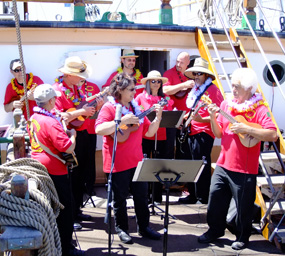 A group of musicians playing instruments on the main deck of BALCLUTHA.