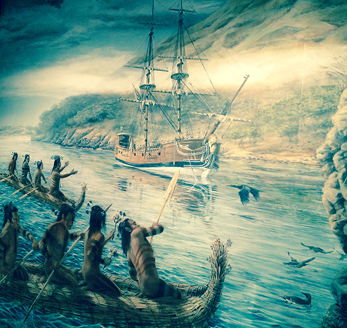 A painted mural depicting a sailing ship being greeted by men paddling tule reed canoes.