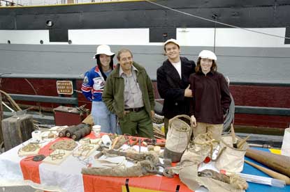 Volunteers and park shipwright standing behind a table displaying knots and items made from canvas.