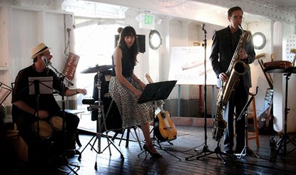 Three musicians performing on a historic ship.
