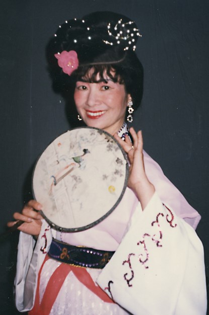 A woman holding a round fan.