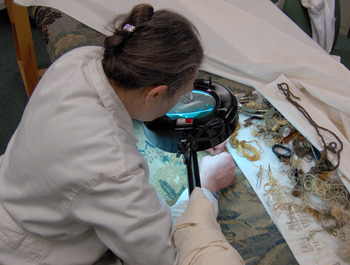 SaintpGaudens NHS museum technician making a repair on an antique tapestry