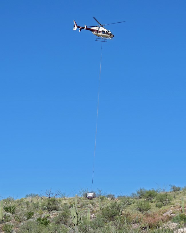 Helicopter using spray ball to treat buffelgrass