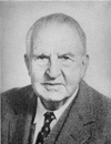 Black and white portrait photo of a man in suit and tie.