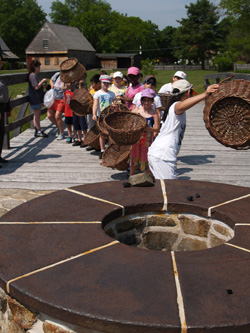 School children roleplaying as workers loading the top of the blast furnace with charcoal