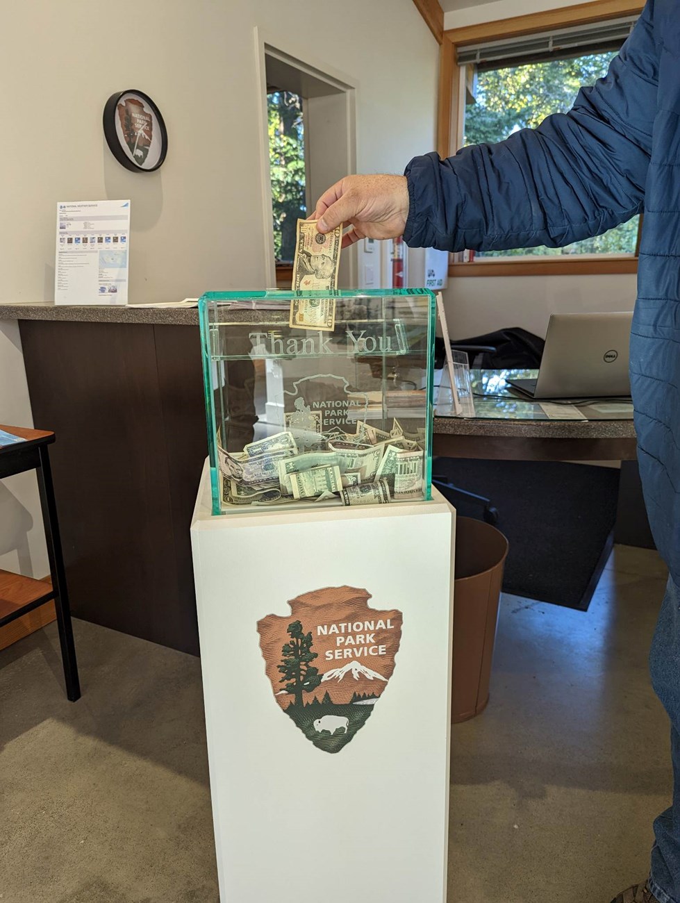 a hand putting money into a donation box