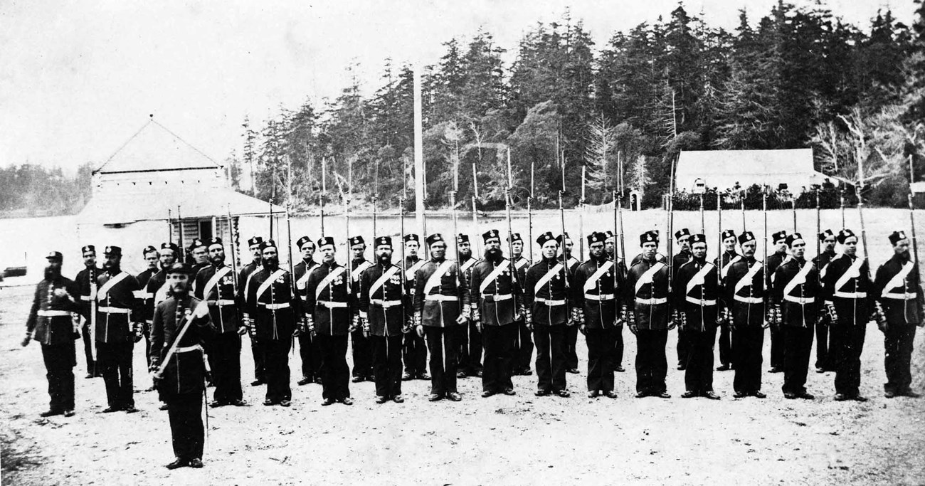 Black and white photograph of a large group of soldiers in uniform on a parade ground.