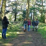 A group of young people are videotaped walking on a trail.