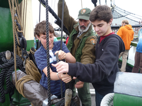 Two students learn how to tie off a line from a member of Friendship's crew.