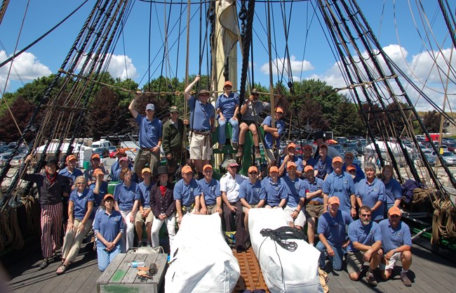 A large group of volunteers line up along the deck of the FRIENDSHIP OF SALEM.