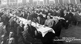 Rows of men sitting at tables at a formal banquet