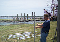 A workman assembles fencing on Central Wharf, with the replica tall ship Friendship in the background