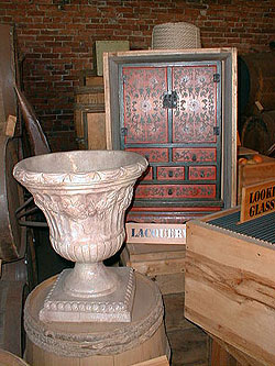 A large alabaster urn sits next to a red and black lacquered Chinese cabinet