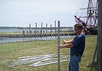 A workman assembles fencing on Central Wharf, with the replica tall ship Friendship in the background