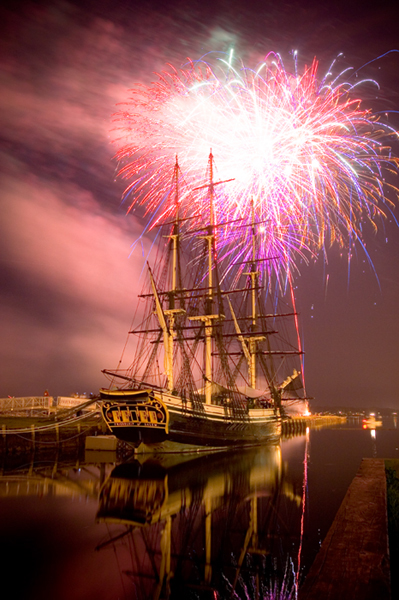 Fireworks explode behind the tall ship Friendship of Salem