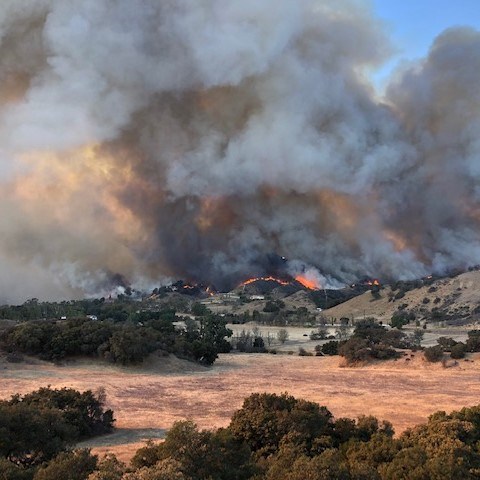 a large wildfire in a hilly landscape