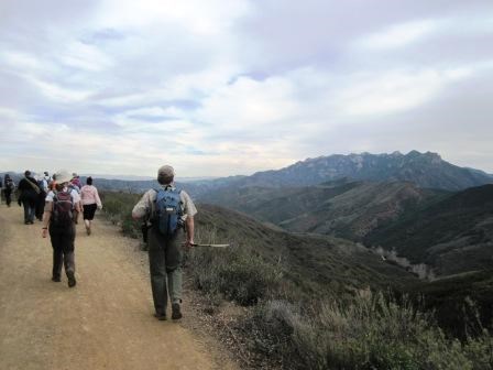 Hikers travel along the Backbone Trail and look towards the rugged cliffs of the Circle X Ranch area.