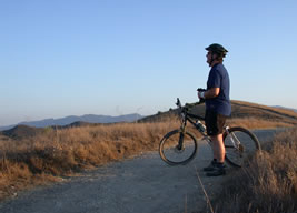 A mountain biker stands next to his bike and looks out over a view of the hills of Cheeseboro Canyon. A mountain biker stands next to his bike and looks out over a view of the hills of Cheeseboro Canyon.