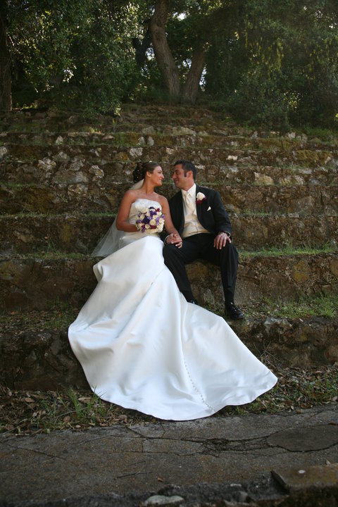 A couple enjoys a romantic moment in the park on their wedding sitting on the steps at Peter Strauss Ranch.