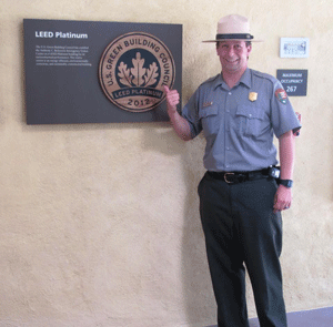 A park ranger points to a LEED Platinum plaque in the Visitor Center.