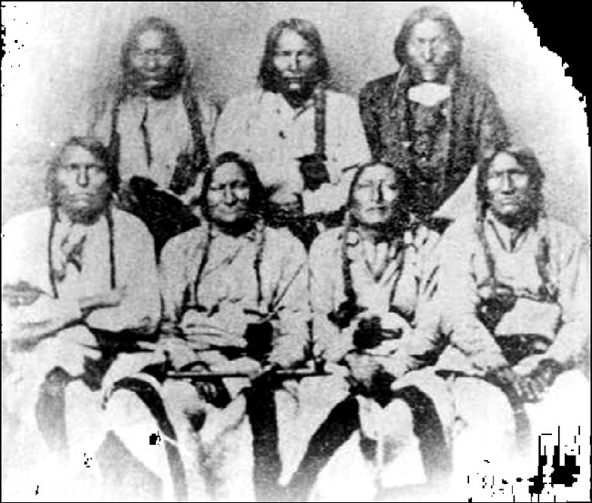 Picture of seven Cheyenne and Arapaho Chiefs at the Camp Weld Conference. Black Kettle is seated holding a pipe.