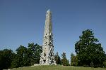 A tall granite obelisk pierces a deep blue sky