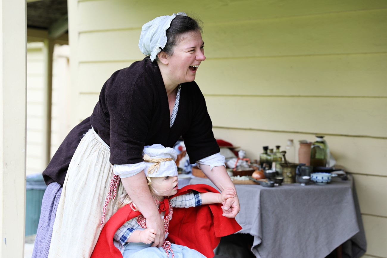 A living history interpreter and her daughter dress in 18th century clothing to talk about the lives of women and children in encampments.