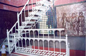Standing in enclosed chamber, second floor of Saratoga Monument, looking at stairs going up.  A young child stands in front of the stairs.