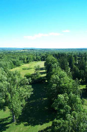 Looking south, the scene is dominated by the green of trees and lawn, then more trees into the distance.  Halfway up the picture, the blue-green hills give way to high, thin clouds and rich blue skies.