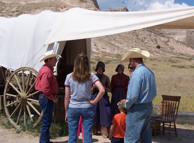 Living history volunteers and visitors at covered wagon