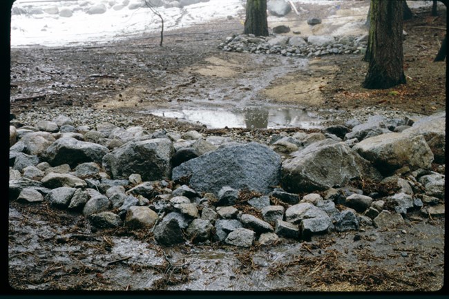 Line of granite rocks form a small dam across a gulley to check the flow of water.