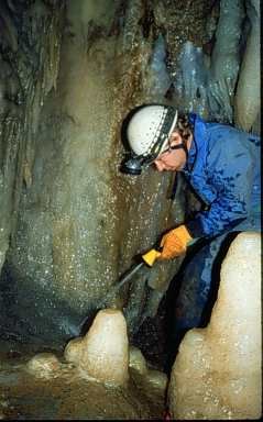 Volunteer helping clean muddied formation in Soldiers Cave