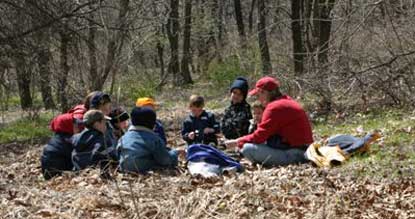 Teacher and students sitting in the woods.