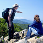 A park ranger and a visitor enjoy a scenic splendor high atop a rocky peak in Shenandoah.