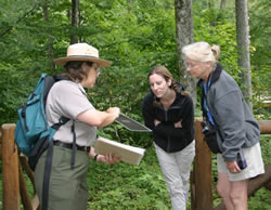 A ranger shows two visitors some photos during a tour of historic Rapidan Camp.