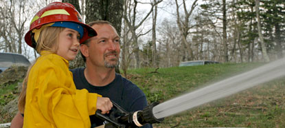 A child gets to experience holding a fire hose at Shenandoah's National Junior Ranger Day.