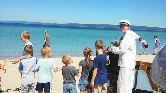 Ranger in sailor uniform is surrounded by kids watching the lyle gun demo