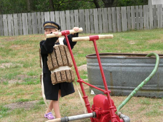 A young park visitor, dressed in a US Life-Saving Service uniform and cork life jacket, pretends to pump water from a sinking ship.