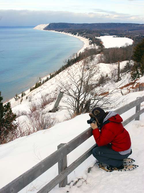 Visitor enjoys the view at the end of the Empire Bluff Trail during a ranger-led snowshoe hike.