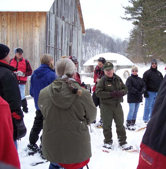NPS Ranger Bill Herd and snowshoers explore historic farm in Lakeshore.