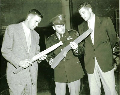 Examining a rough wooden stock blank and a semi-finished shaped stock in WWII