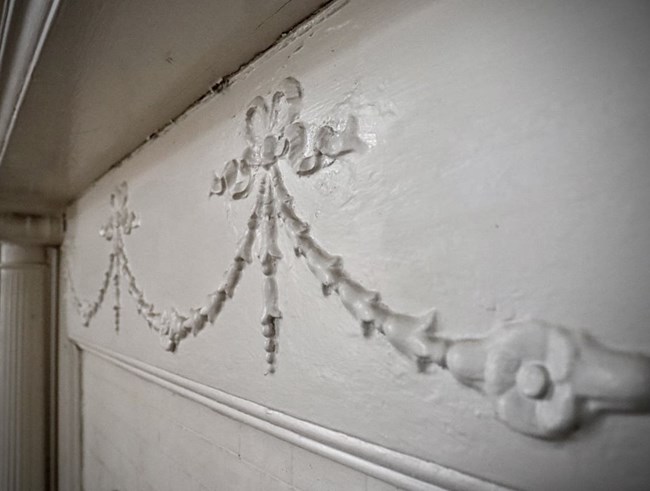 An intricate ivy pattern carved above a fireplace.